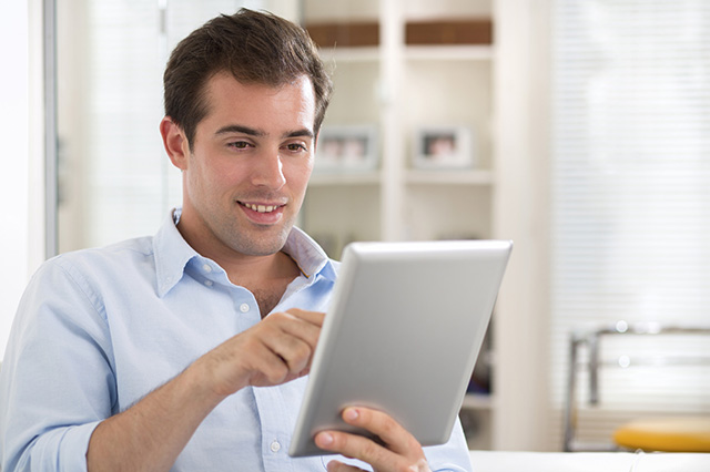Man using tablet pc on couch at home